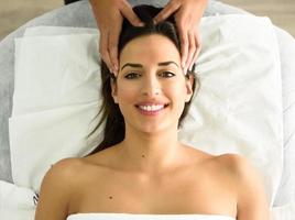 Young smiling woman receiving a head massage in a spa center. photo