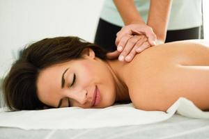 mujer joven recibiendo un masaje de espalda en un centro de spa.