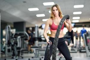 Woman with battle ropes exercise in the fitness gym. photo