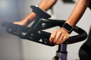 Mujer en un gimnasio haciendo spinning o ciclo interior con reloj inteligente foto