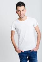 Smiling young man standing against white background photo