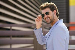 Young handsome man wearing sunglasses in urban background photo