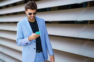 Man walking down the street using his smartphone with a happy expression photo