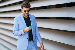 Man walking down the street using his smartphone with a happy expression photo