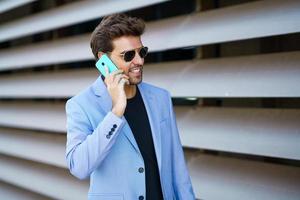 Man walking down the street using his smartphone with a happy expression photo