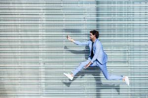 Hombre vestido con traje hace un selfie con un teléfono inteligente mientras salta foto