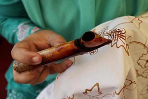 Close Up hand to make batik tulis on the fabric with canting photo