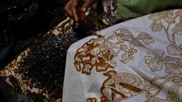 Close Up hand to make batik tulis on the fabric with canting photo