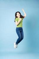 Portrait of beautiful young asian girl jumping up, isolated on blue background photo