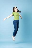 Retrato de una hermosa joven asiática saltando, aislado sobre fondo azul. foto