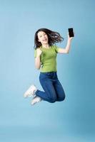 Portrait of beautiful young asian girl jumping up, isolated on blue background photo