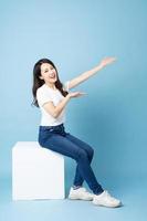 Asian girl portrait sitting on white cube, isolated on blue background photo