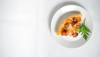 a slice of Italian pizza on a white plate with some tasty topping on it. a studio shot of a delicious food with copy space. photo