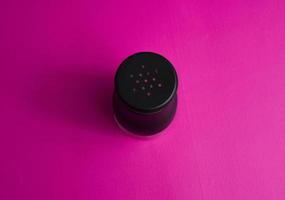 salt or pepper shaker in oblique and stand up from top view. seasoning powder container in white and black. food condiment shaker on pink background.