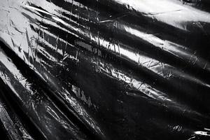 una envoltura de plástico elástico transparente sobre fondo negro. textura realista de envoltura de plástico para superposición y efecto. patrón de plástico arrugado para un diseño creativo y decorativo. foto