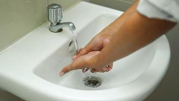 lavarse las manos en el fregadero blanco para mantener su mano limpia y estéril. eliminar de las bacterias adheridas. foto