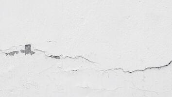 a shot of a cracked white wall of the building. a worn wall for a construction background texture collection. photo