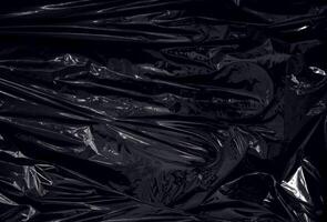 a transparent plastic wrap on black background. realistic plastic wrap texture for overlay and effect. wrinkled plastic pattern for creative and decorative design. photo