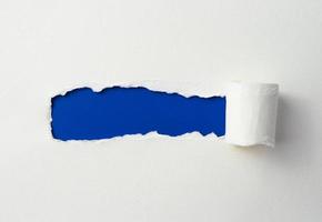 marco de papel rasgado con los lados rasgados. un agujero azul de rasgado en el papel blanco. papel rasgado realista con los bordes rasgados para copiar texto y espacio. foto