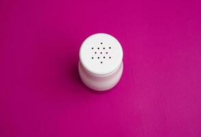 salt or pepper shaker in oblique and stand up from top view. seasoning powder container in white and black. food condiment shaker on pink background. photo