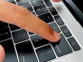 a hand on top of the keyboard. working from anywhere using a laptop. photo