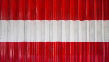 el aspecto detallado de la puerta plegable roja y blanca. la vista en primer plano de la tienda cerrada mediante una puerta plegada. el fondo texturizado del material de la calle. foto
