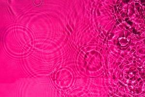 abstract calm rippling water of the rain drop texture in pink color. a background pattern of the clear liquid water for creative design. photo