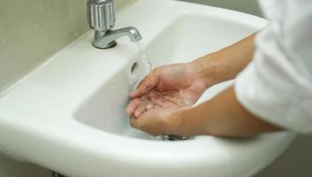 lavarse las manos en el fregadero blanco para mantener su mano limpia y estéril. eliminar de las bacterias adheridas. foto