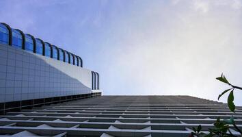 un edificio rascacielos que tiene muchos materiales de vidrio con un fondo de cielo azul. el edificio alto en el casco urbano. foto