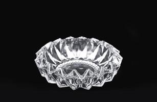 luxurious crystal ashtray isolated on black background. a single transparent glass container for minimalist home decoration. photo