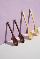 four wooden spoons standing on the lavender wall. a studio shot of the organic utensils. suitable for advertisement. photo