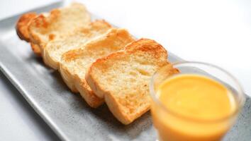 the golden brown toasted bread served with a cup of cheese sauce. a typical of breakfast menu for western. photo