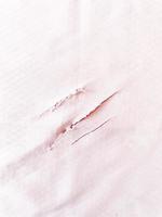 rasgar tela en rosa. material texturizado rasgado. un primer plano de un tejido triturado. las marcas de garras únicas en el material de algodón. color rosa bebé. foto