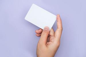 a right hand holding an empty white space on a lavender background. a mockup that is suitable for business or identity mockup use.
