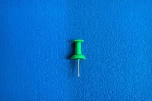 a thumbtack on a blue background. realistic pushpin for pinning paper and notes on board. office stationery collection. photo