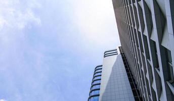 un edificio rascacielos que tiene muchos materiales de vidrio con un fondo de cielo azul. el edificio alto en el casco urbano. foto