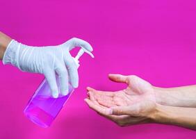 a gloved hand that sprays hand sanitizer on the other hand to protect it from bacteria and keep it hygenic. photo