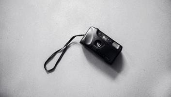 top view of an old camera with black color and on a clean background. a vintage camera with a short hand strap in black. photo