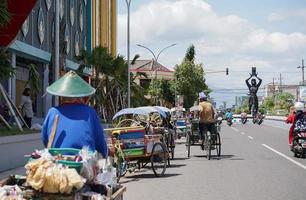ponorogo, indonesia 2021 - hombre conduce bicitaxi con pasajero foto