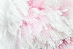 the closeup view of the artificial fur in the uneven dyed color of white and pink. messy yet fluffy surface material for background. photo