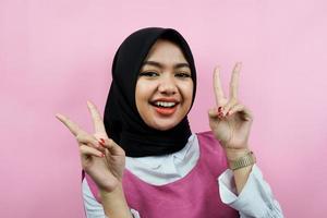 Primer plano de una joven y bella mujer musulmana, sonriendo con dos dedos, Victoria, aislado