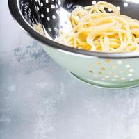espaguetis frescos cocidos en un colador de acero inoxidable