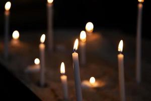 Candle light. Candles light in dark background. Candle flames in catholic church. Bokeh effect. photo