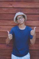 asian man sign good thumb with funny face against old wooden background photo