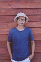 asian wearing clothes hat standing against wooden wall with high self confidence photo