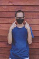 asian man wearing face protection mask standing against wooden wall photo