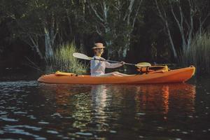 Mujer navegando en kayak de mar en el canal del bosque de manglares foto