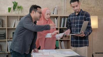 jonge startup-collega's die islamitische mensen zijn, praten met hun baas over financiële projecten die in een e-commercebedrijf werken. gebruik laptop voor online communicatie via internet in een klein kantoor.