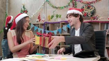 Überraschen Sie das Team und den Chef von zwei Mitarbeitern, indem Sie Geschenke geben, während Sie vor dem Betriebsurlaub am Büroarbeitsplatz arbeiten, ist für die Weihnachtsfeier und die Neujahrsfeier dekoriert.