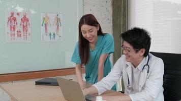 Healthcare team partners. Two uniformed young Asian ethnicity doctors are coworkers discussing medication in hospital's clinic office. Specialist persons are experts and professionals. video